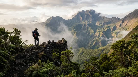 Randonneur solitaire face au Piton des Neiges depuis un sentier volcanique de La Réunion