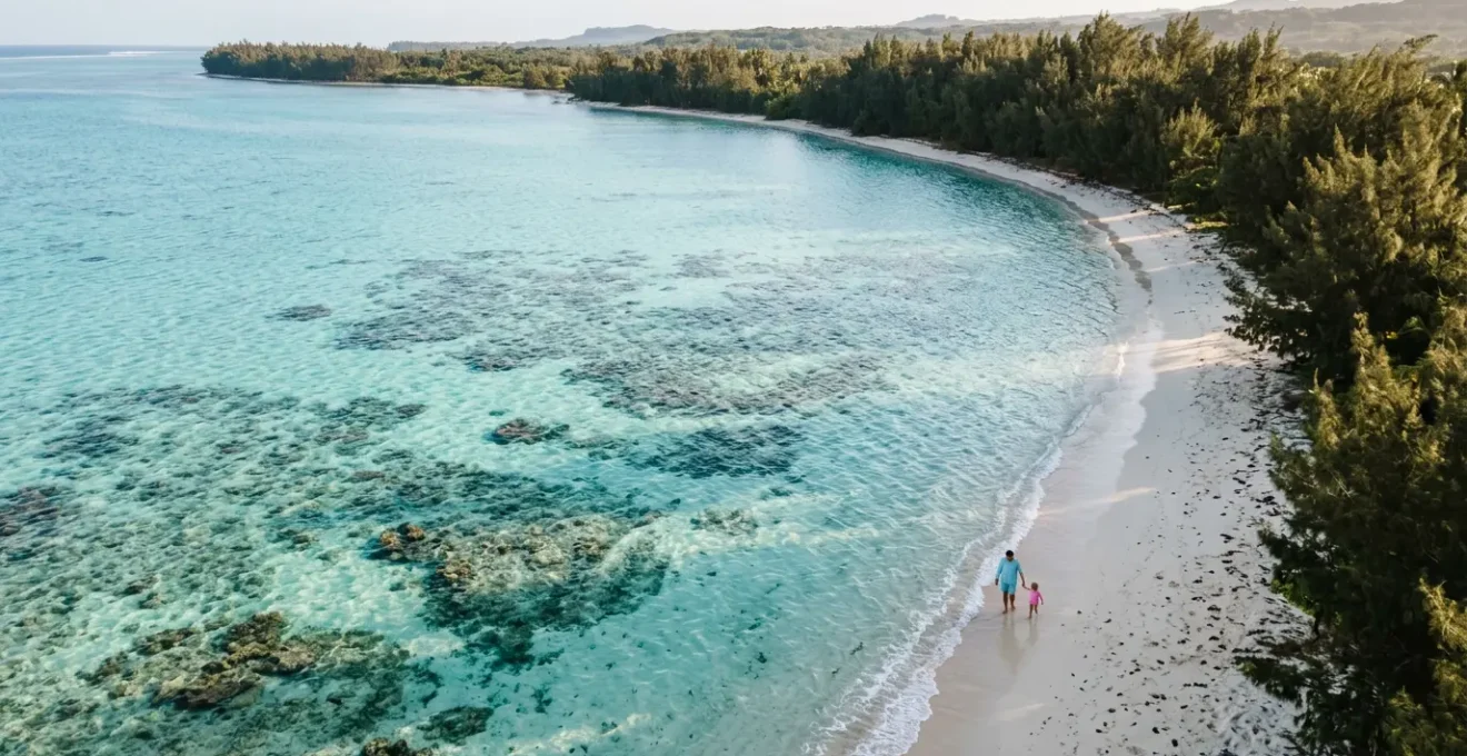 Famille avec jeunes enfants jouant dans les eaux turquoise peu profondes du lagon de l'Ermitage