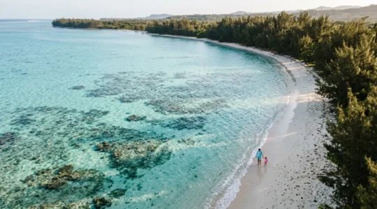Famille avec jeunes enfants jouant dans les eaux turquoise peu profondes du lagon de l'Ermitage