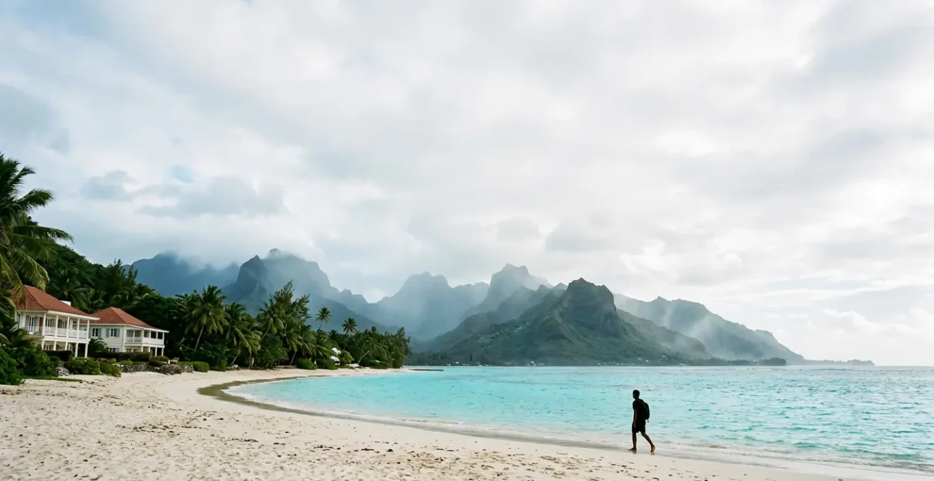 Vue panoramique d'une plage de sable blanc avec lagons turquoise et montagnes volcaniques à l'arrière-plan, représentant le paradis tropical européen de La Réunion